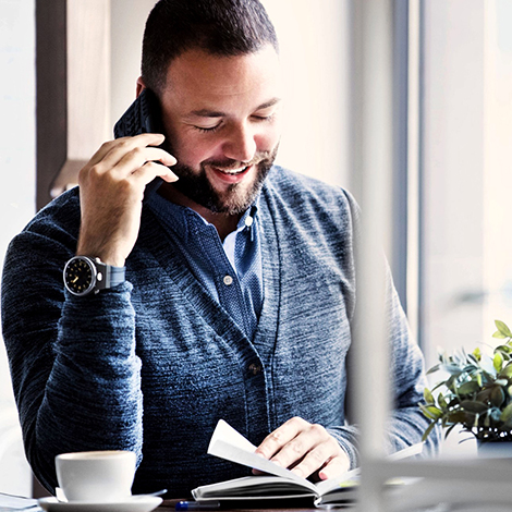 man in blue sweater on the phone reading a book